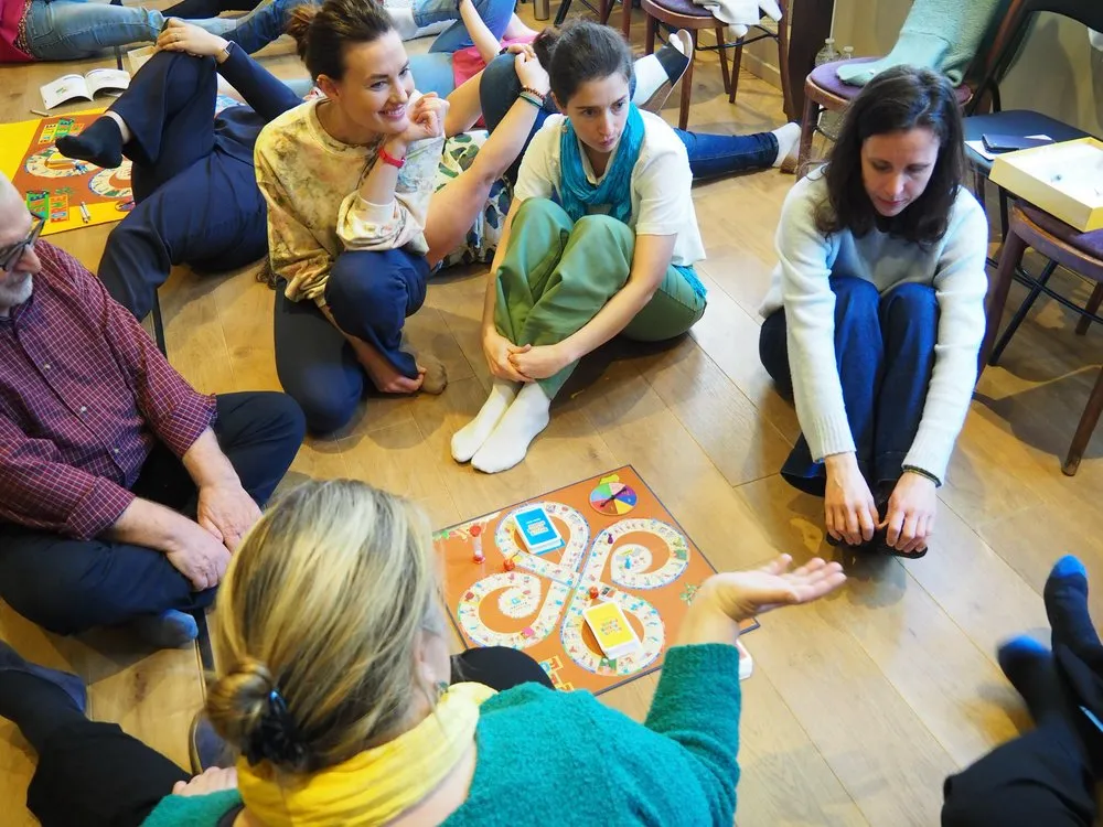 Des participants assis par terre en cercle autour de plateaux de jeu