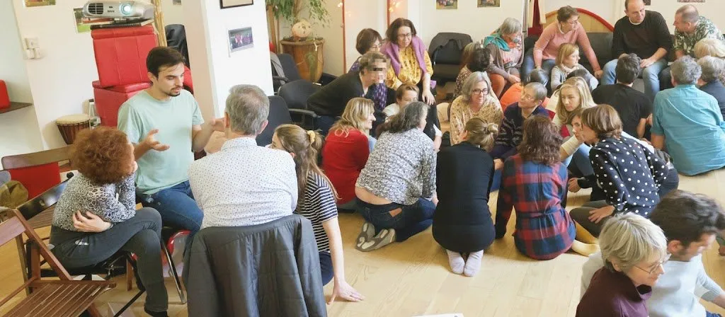 Participants d’un atelier assis en cercle dans une salle, à l’écoute d’un animateur