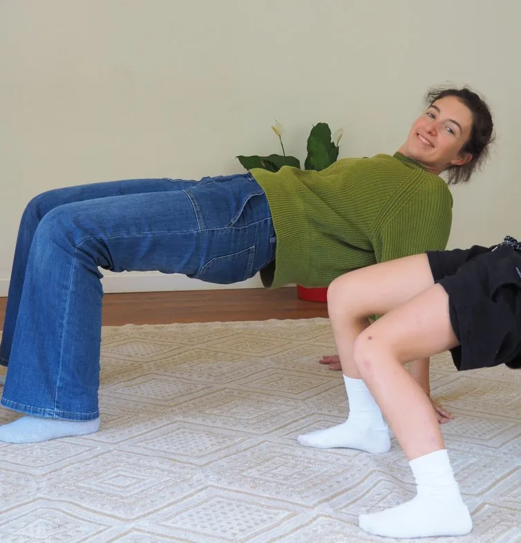 Deux stagiaires pendant un exercice corporel au sol, l’une en appui sur les mains et les pieds en position de pont