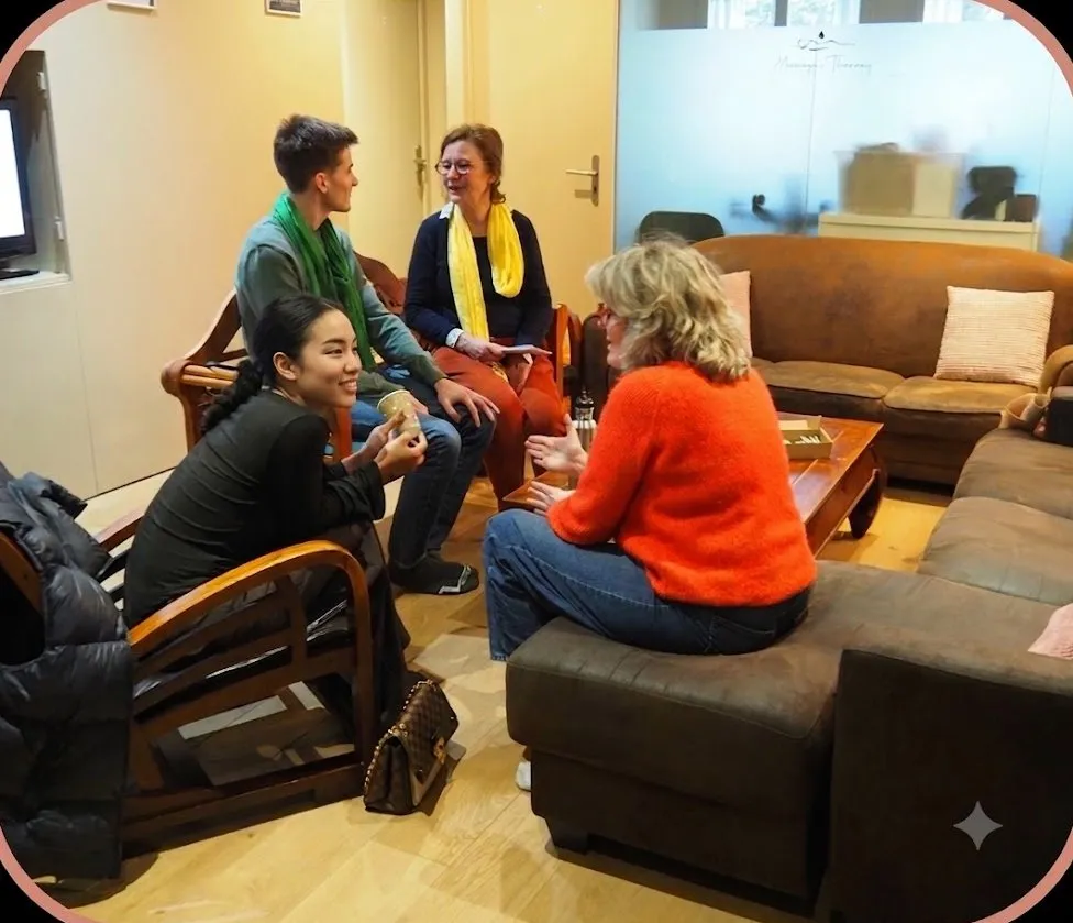 Quatre personnes en conversation dans les fauteuils d’un salon