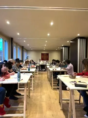Salle de formation de l’école : des stagiaires concentrés écrivent à de longues tables pendant une validation des connaissances