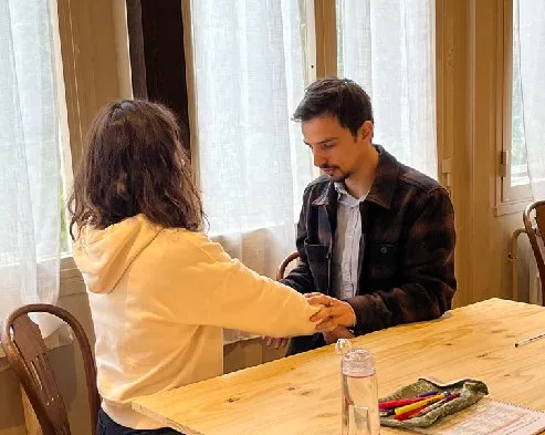 Séance en tête-à-tête : un praticien teste la force musculaire du bras d’une participante, assis à une table